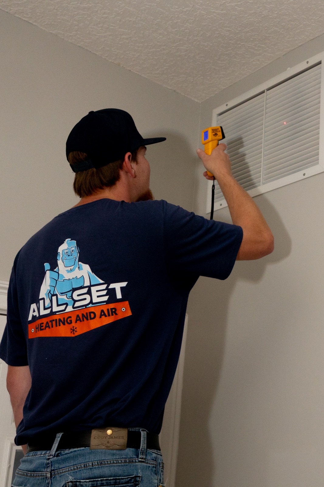 All Set Heating and Air technician using an infrared thermometer to diagnose vent airflow